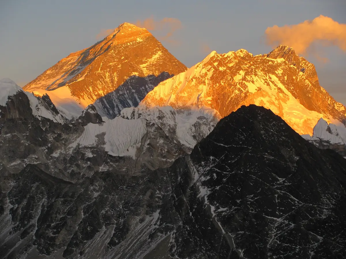 Il Monte Everest e le cime vicine che brillano di arancione alla luce del sole al tramonto