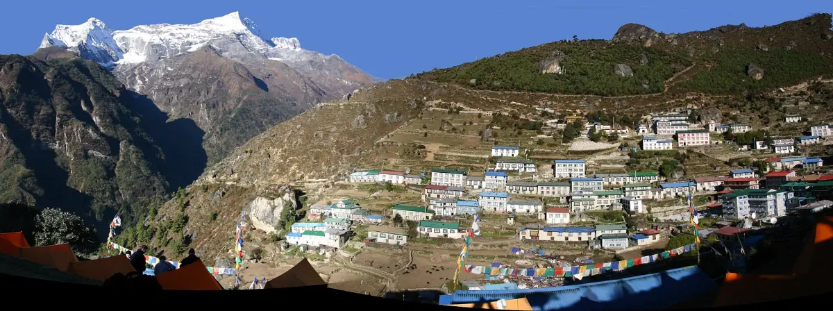 Namche Bazaar sul suo versante terrazzato con bandierine di preghiera e il massiccio del Kongde Ri sopra